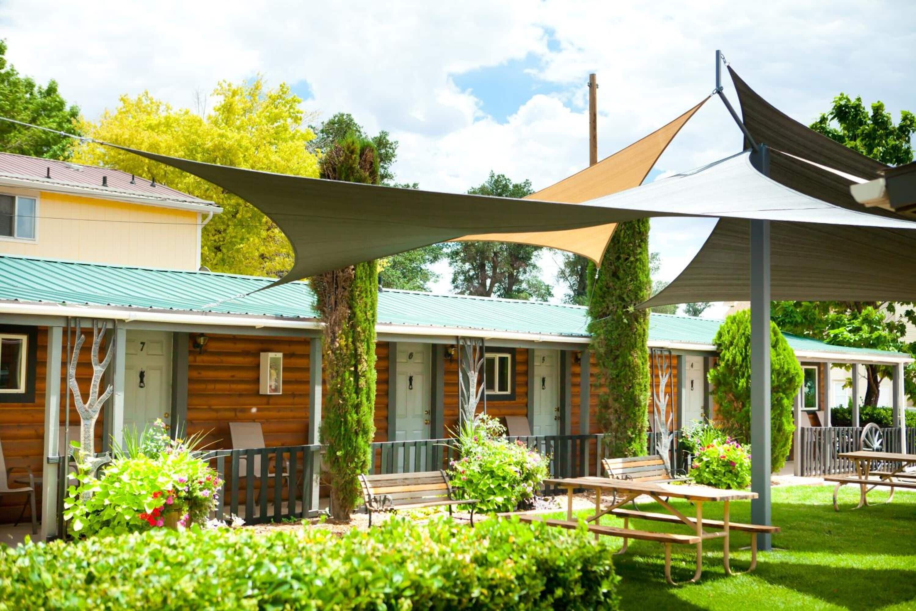 A row of log cabin-style cabins with outdoor seating areas, surrounded by lush greenery.