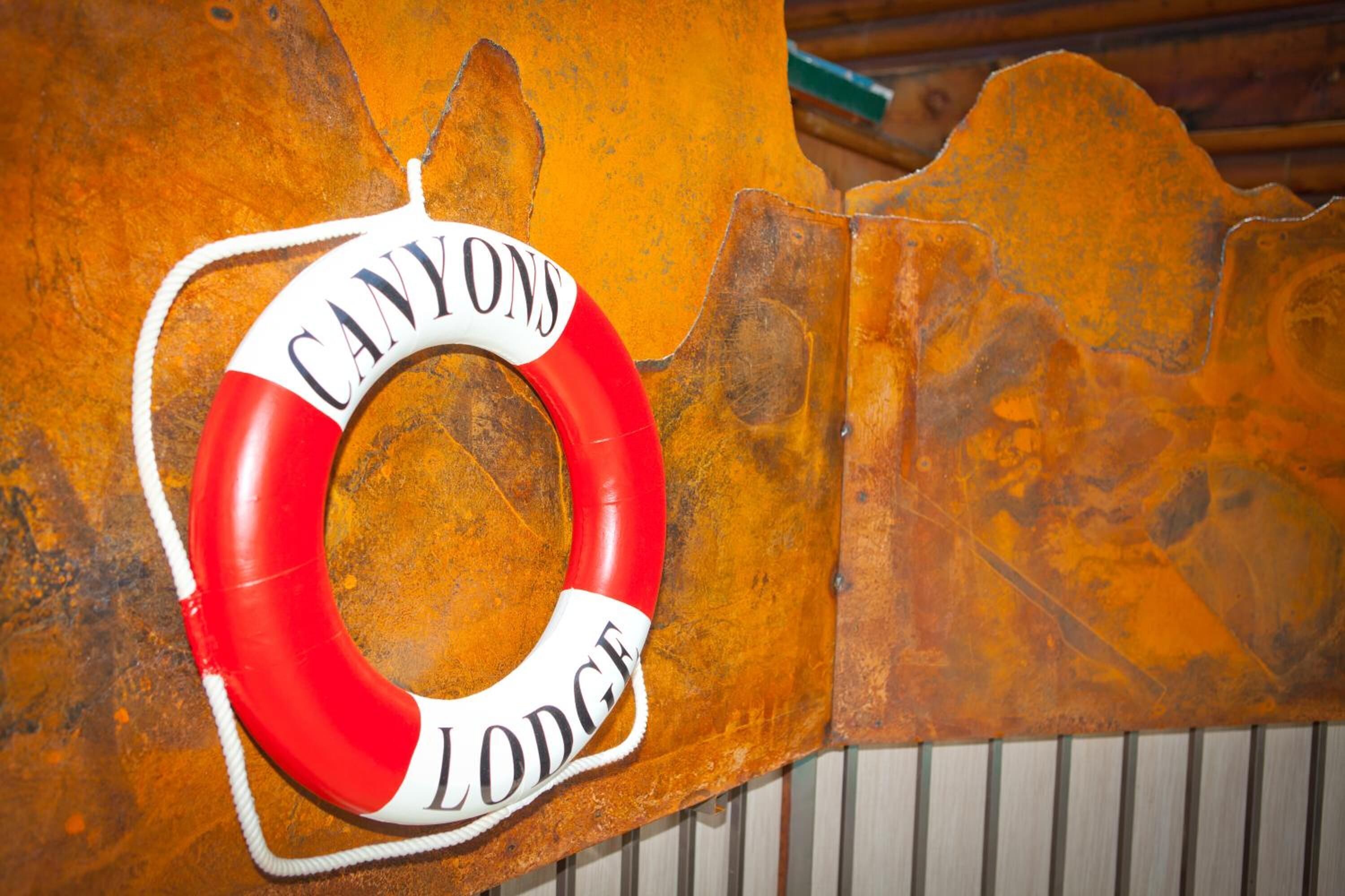 A lifebuoy with the text "CANYON LODGE" on a rustic wall.