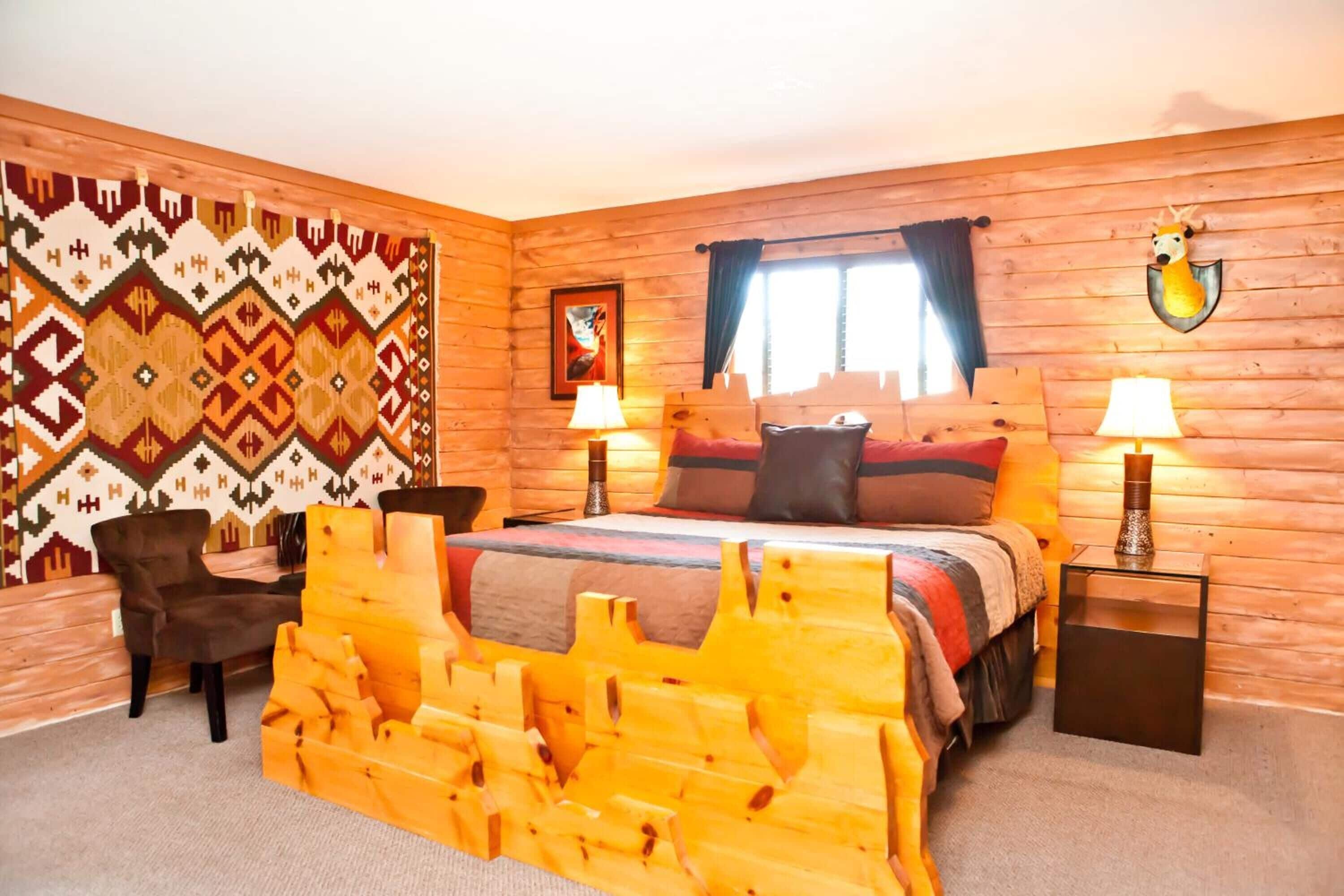 A wooden-themed bedroom with a bed, two bedside tables with lamps, a chair, and a patterned wall.
