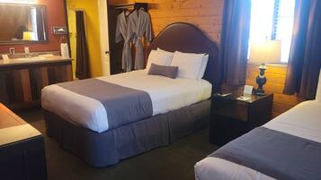 A hotel room with a large bed, a bedside table with a lamp, a wooden headboard, and a mirror above the bed.