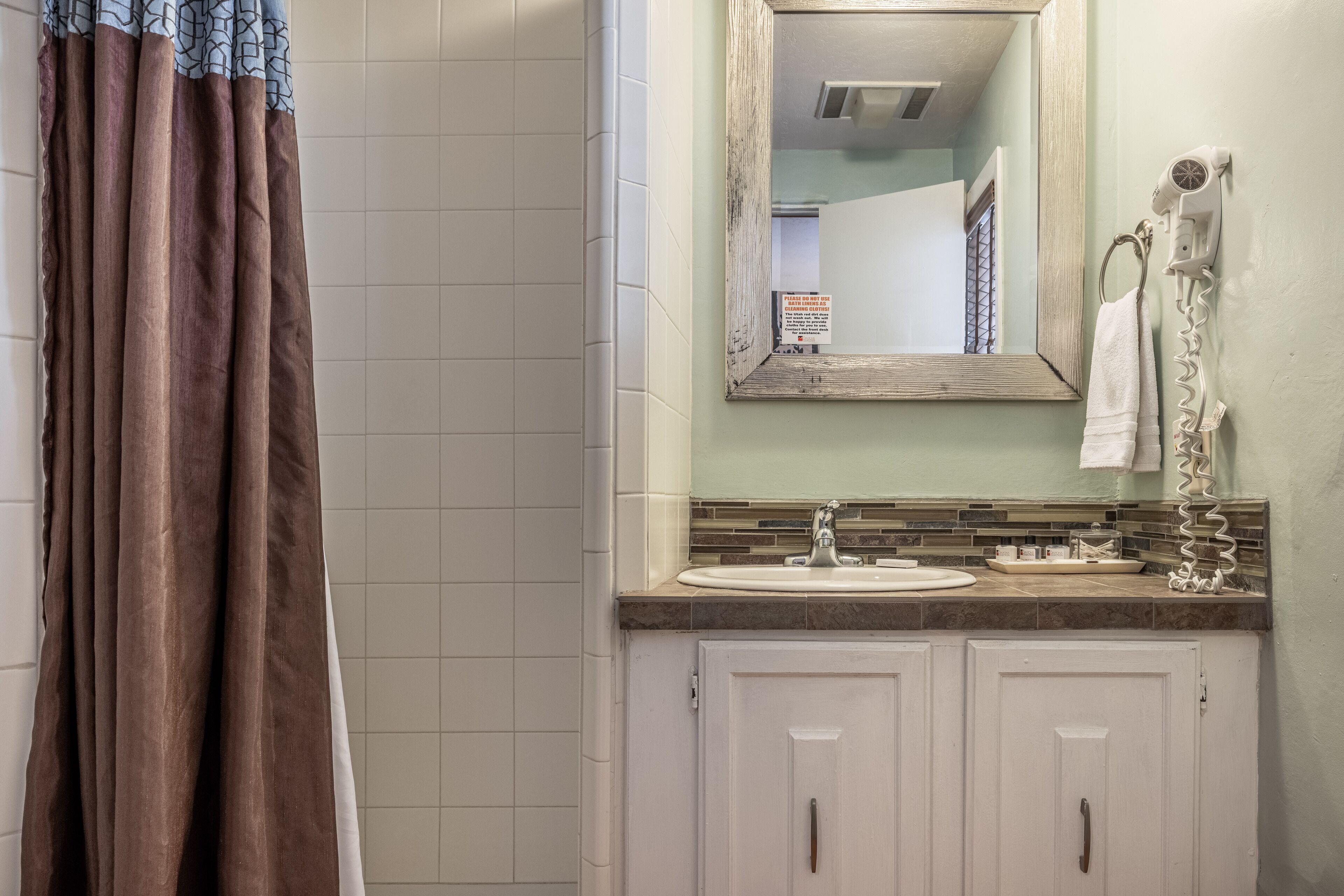 Une salle de bain équipée d’un rideau de douche, d’un lavabo, d’un miroir et d’un porte-serviettes.