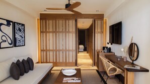 A modern hotel room with a sofa, a wooden table with a bowl, a TV, and a mirror. - Avantgarde Refined Yalıkavak (Bodrum)