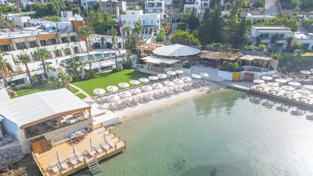 An aerial view of a resort with a clear pool, sun loungers, and a covered dining area. - Avantgarde Refined Yalıkavak (Bodrum)