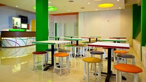 Un espacio interior bien iluminado con varias mesas y taburetes, dispuesto para una comida informal.