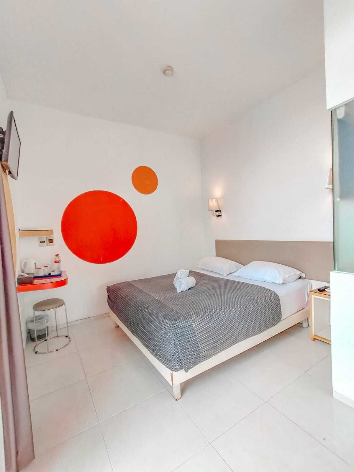 Una camera d'albergo moderna con un letto grande, una scrivania e una lampada fissata alla parete.