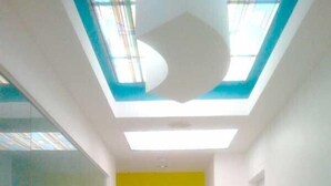Un pasillo con tragaluces, una puerta marcada con el número 3 y una pared amarilla.