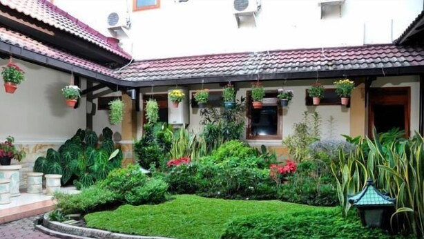 A courtyard with a tiled roof, potted plants, and a well-maintained lawn. - Hotel Armi (Malang)