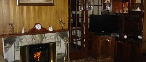 Ein Wohnzimmer mit Kamin, Fernseher und Holzwandverkleidung.