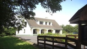 Un bâtiment blanc avec un toit à deux versants, une allée pavée et une clôture en bois.