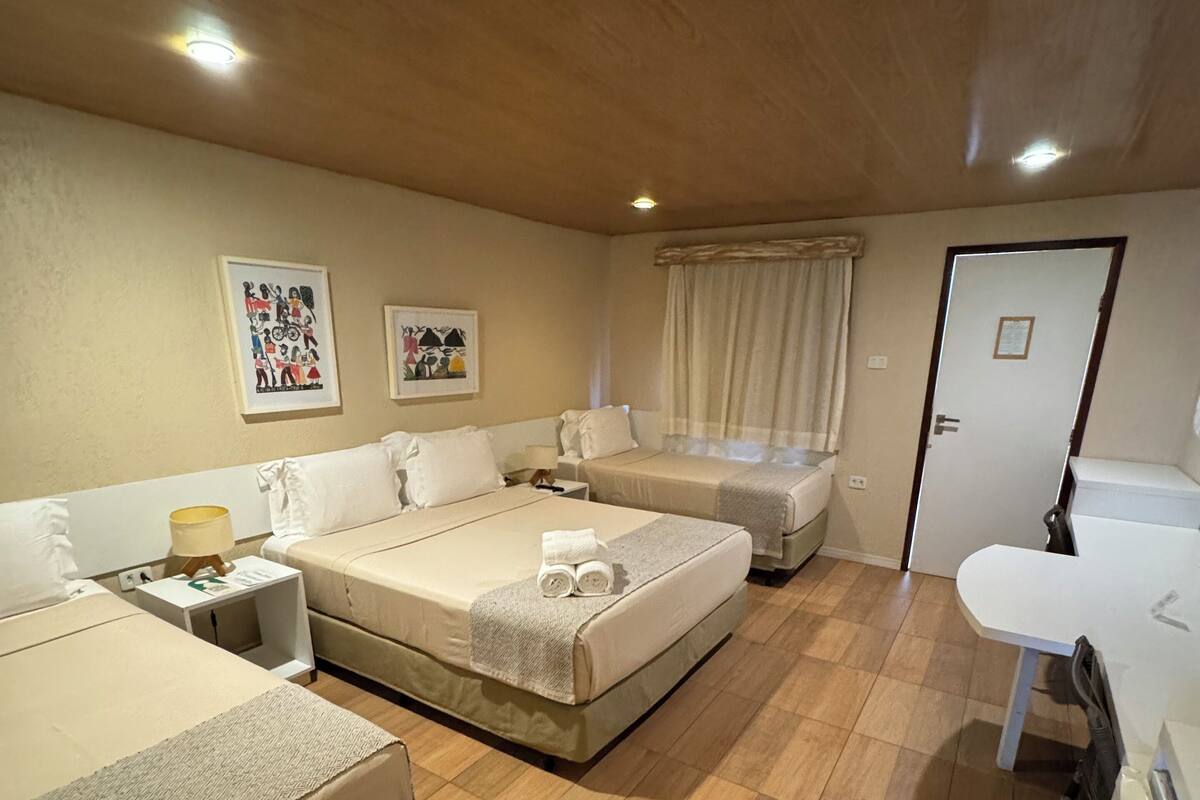Ein Hotelzimmer mit zwei Betten, einem Schreibtisch, einem Stuhl, einem kleinen Tisch und einem Schrank.