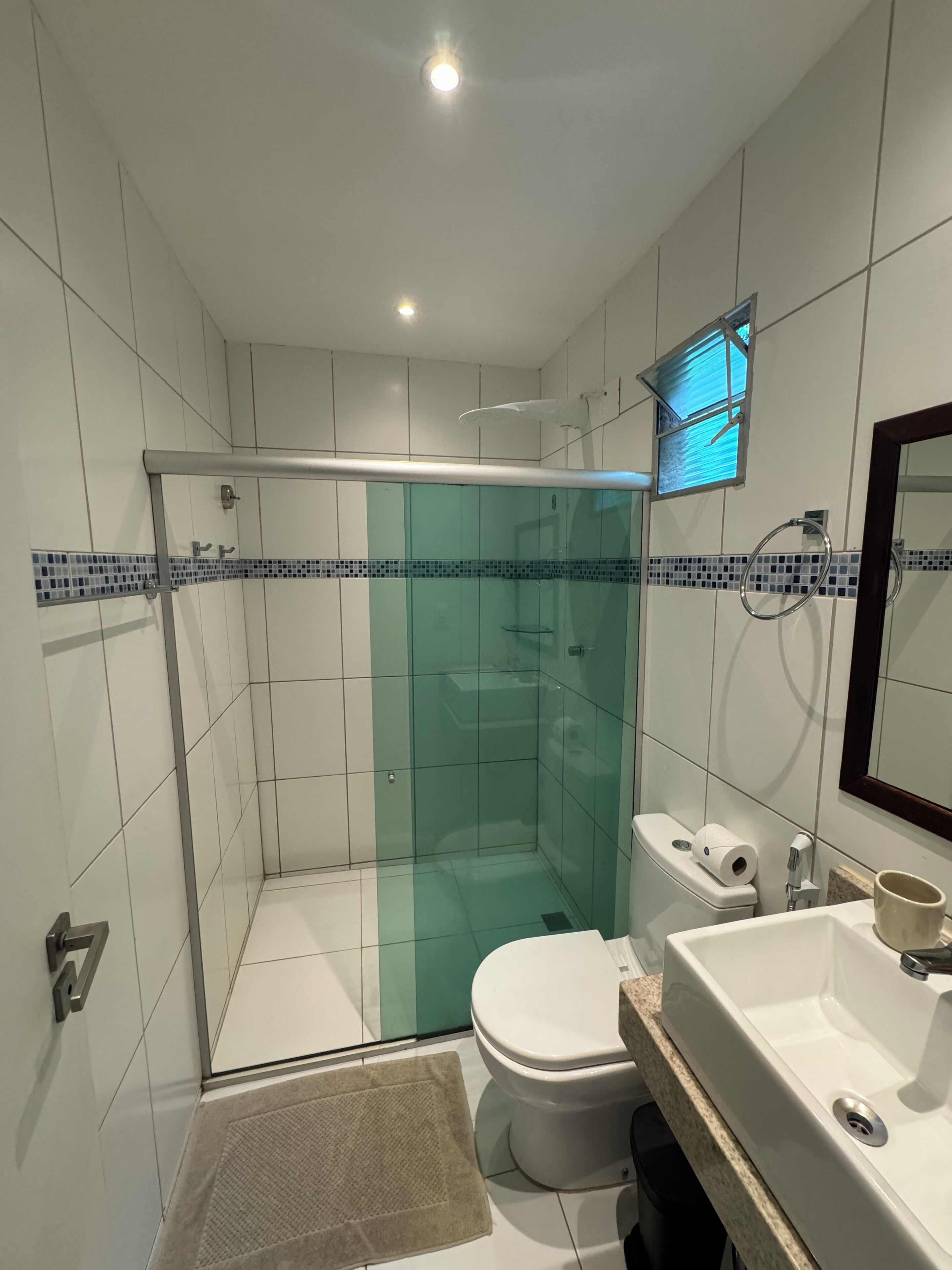 Un baño moderno con ducha de vidrio, inodoro y lavabo con espejo.