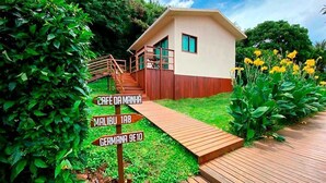 A small, single-story building with a wooden deck leading to a staircase. There are directional signs indicating nearby locations. - Pousada Da Germana (Fernando de Noronha)
