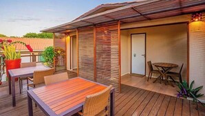 A wooden deck with outdoor furniture, a covered seating area, and a door. - Pousada Da Germana (Fernando de Noronha)