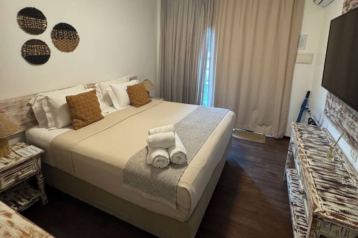 Ein Hotelzimmer mit einem großen Bett, einem Fernseher, einem Schreibtisch und einem Stuhl.