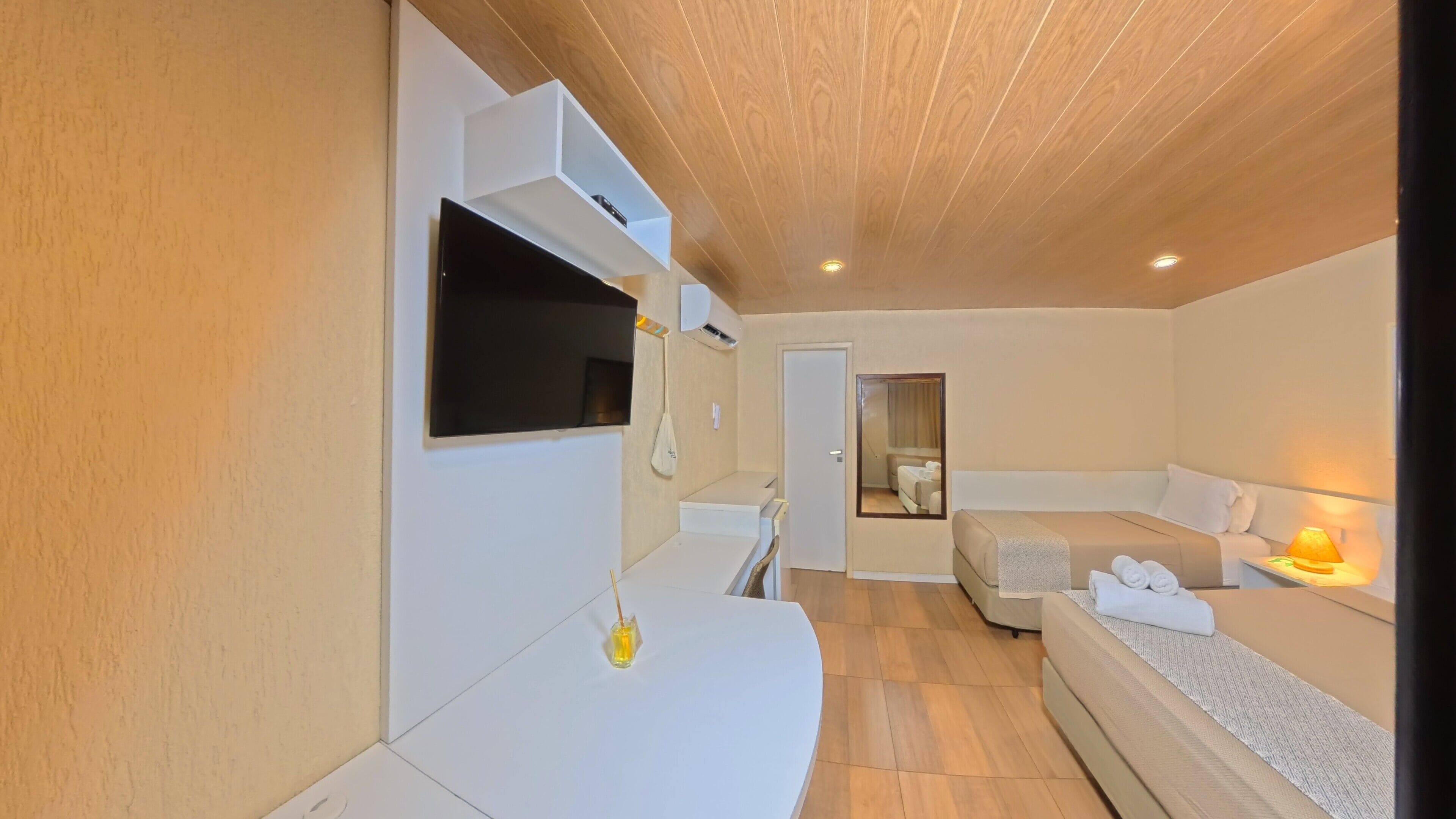 Ein modernes Hotelzimmer mit Flachbildfernseher, einer Couch, einem Bett und einem kleinen Tisch mit Lampe.