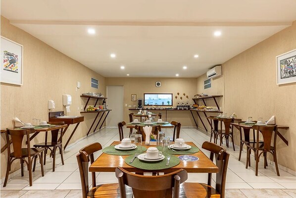 A dining area with multiple tables set for a meal, equipped with chairs, plates, and cutlery. - Pousada Da Germana (Fernando de Noronha)