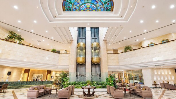 A spacious lobby with a central staircase, a large stained glass window, and multiple seating areas. - Sunlake Waterfront Resort and Convention (Jakarta)