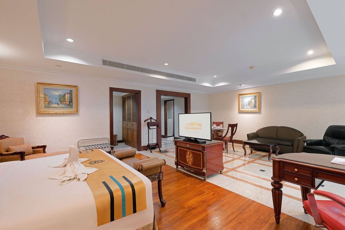 A hotel room with a bed, a desk, a television, a sofa, and a chair.