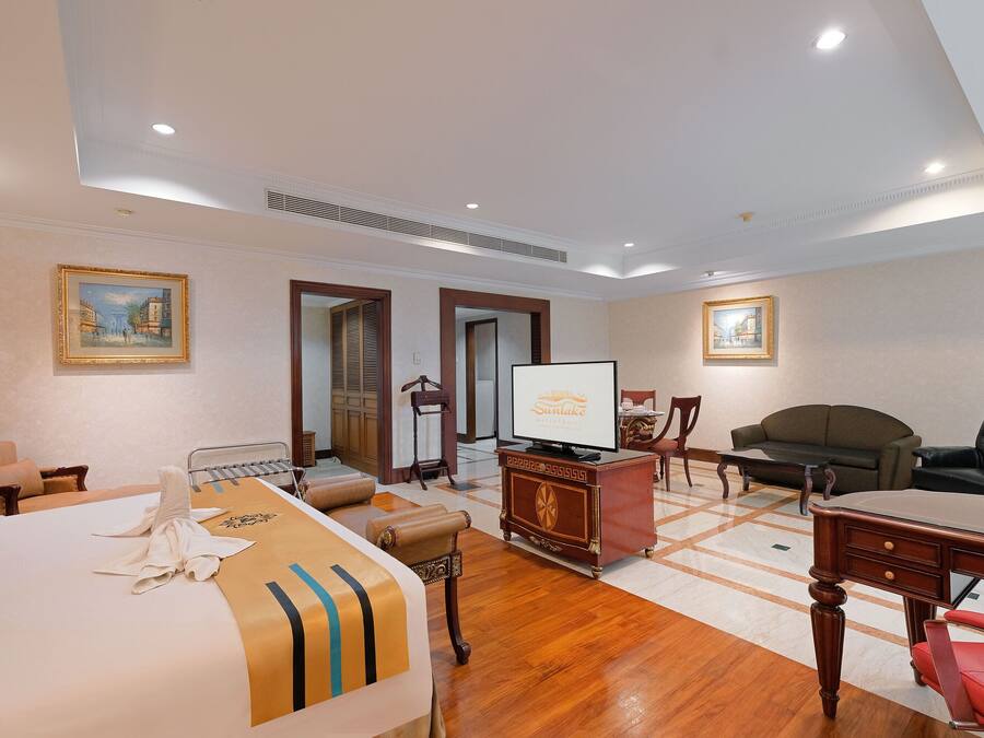 Una habitación de hotel con cama, escritorio, televisor, sofá y sillón.