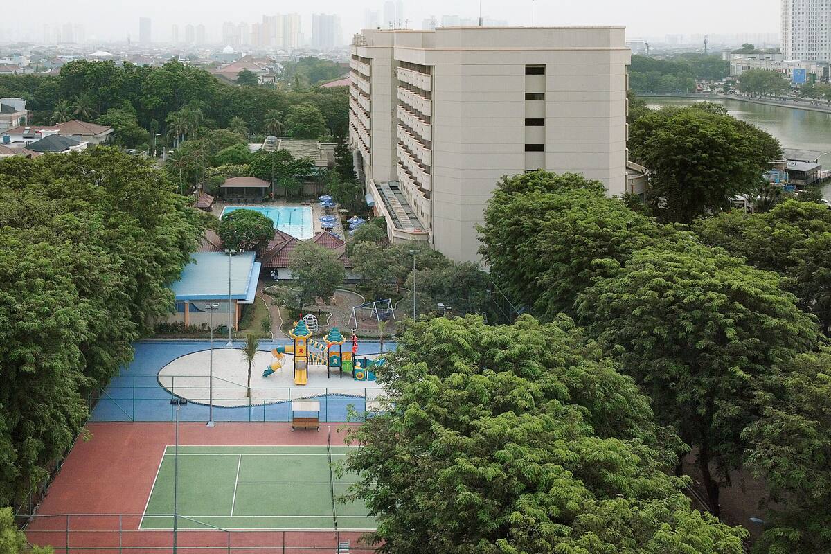 A view of a sports court surrounded by trees, with a building in the background.