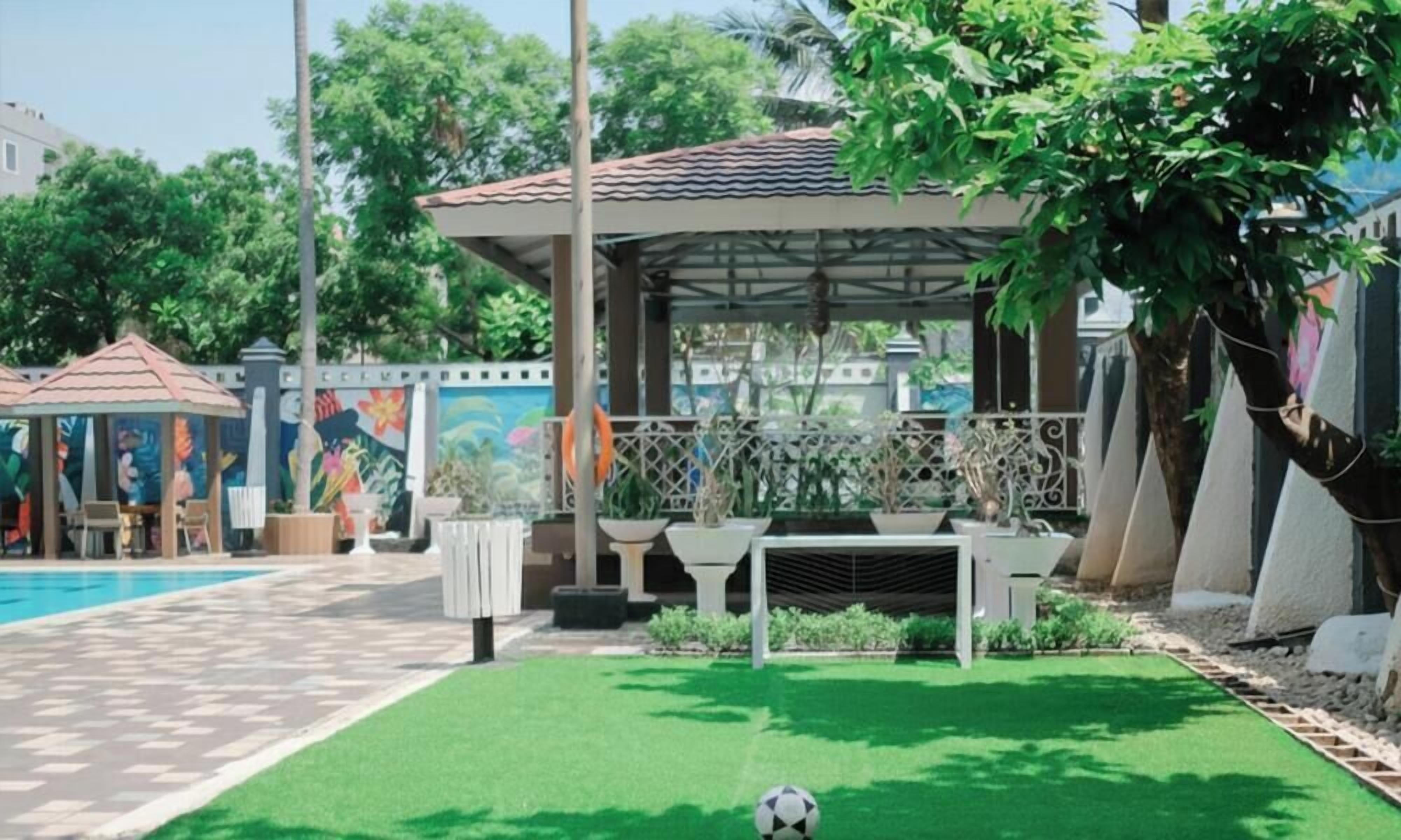 A pool area with a covered seating area, a soccer ball, and a mural on the wall.