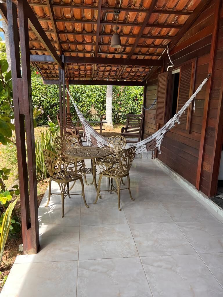Un patio al aire libre con suelo de baldosas, una pérgola de madera, una hamaca y mobiliario de mimbre.