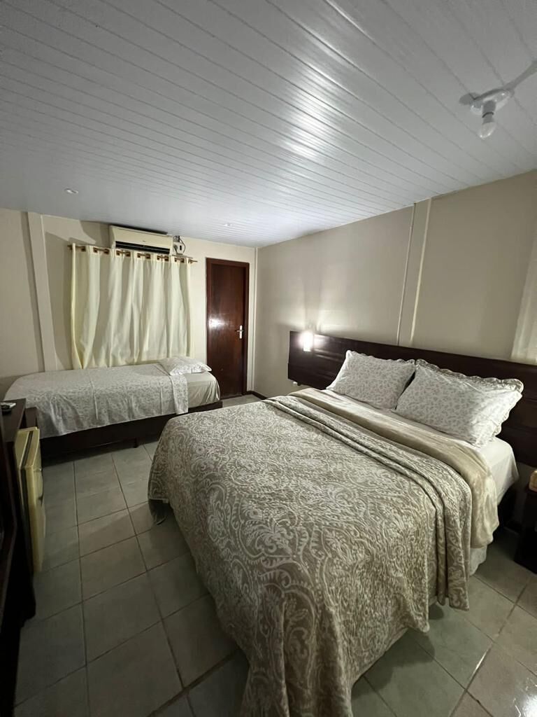 Habitación de hotel con dos camas, cabecera de madera, ventilador de techo y una puerta.