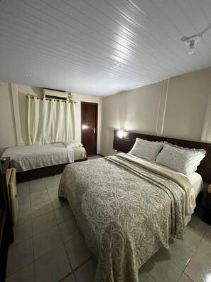 A hotel room with two beds, a wooden headboard, a ceiling fan, and a door. - Pousada do Biu (Fernando de Noronha)