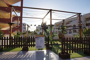 A playground with a wooden structure, a giraffe statue, and a signboard.