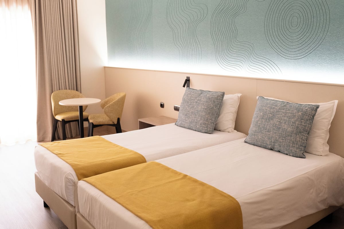 A hotel room with a large bed, two bedside tables, a small desk, and a chair.