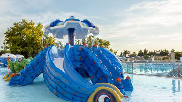 Ein Wasserspielbereich mit einer blauen Rutsche und einem Wellenbecken.