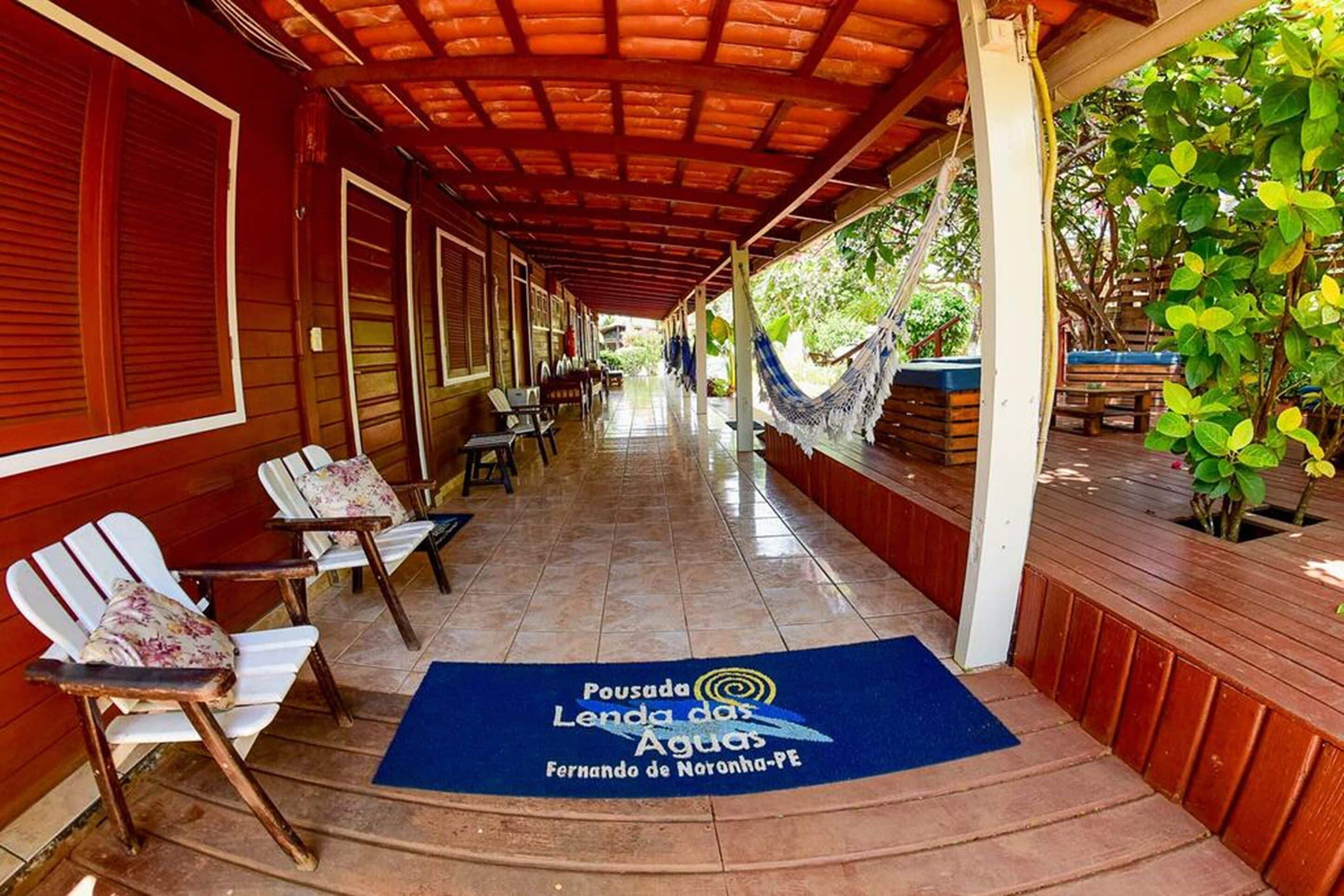 A covered outdoor area with wooden chairs and a blue mat with text.