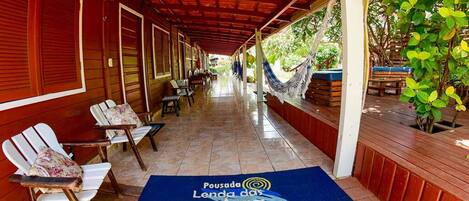 A covered outdoor area with wooden chairs and a blue mat with text.