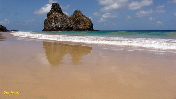 A beach with clear turquoise waters, a sandy shore, and a prominent rock formation in the background. - Pousada Lenda das Águas (Fernando de Noronha)