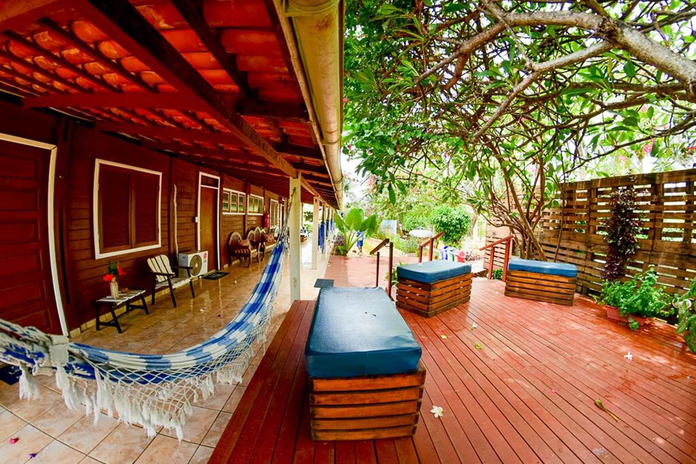 A wooden deck with outdoor seating, a hammock, and a covered area with windows.