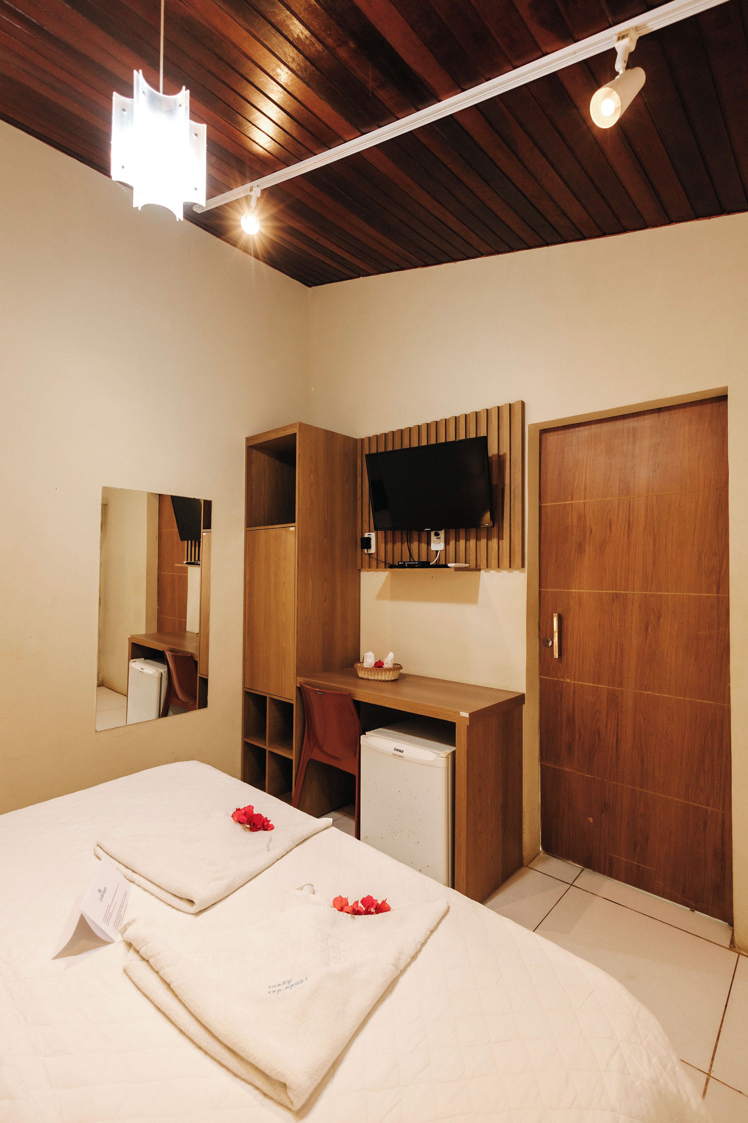 A hotel room with a bed, a desk, a television, and a wardrobe.