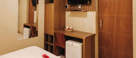 A hotel room with a bed, a desk, a television, and a wardrobe.