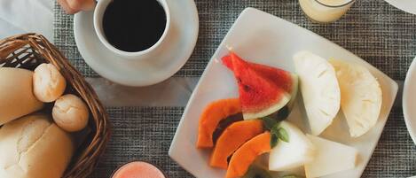 Una mesa de desayuno con platos de comida, una cesta de panes y una taza de café.