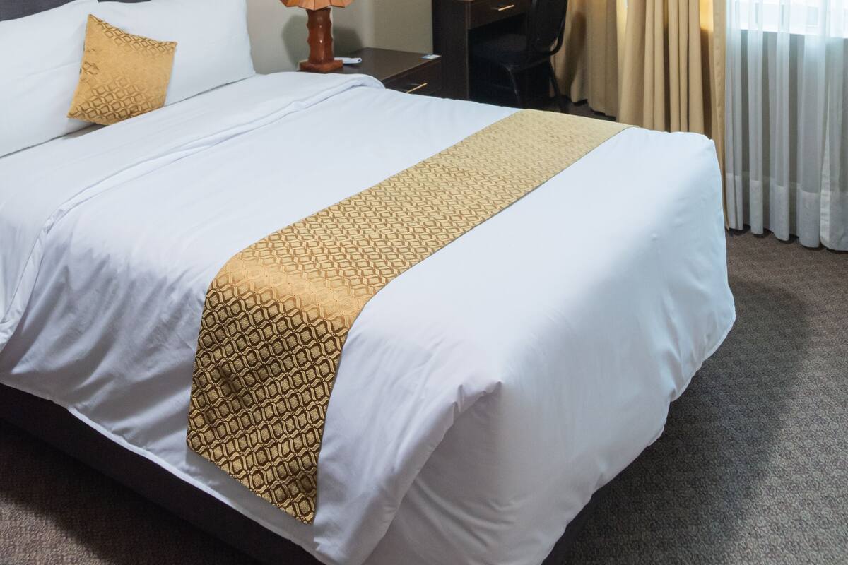 A hotel room with a large bed, a desk, and a chair.