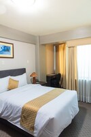 Quarto de hotel com uma cama grande, uma escrivaninha e uma cadeira.