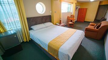 Ein Hotelzimmer mit einem großen Bett, einem Schreibtisch, einem Stuhl, einer Couch und einem Kleiderschrank.