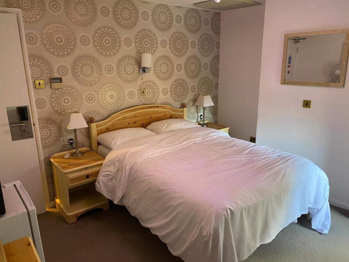 A neatly made bed with white linens, a wooden headboard, and two bedside tables with lamps.