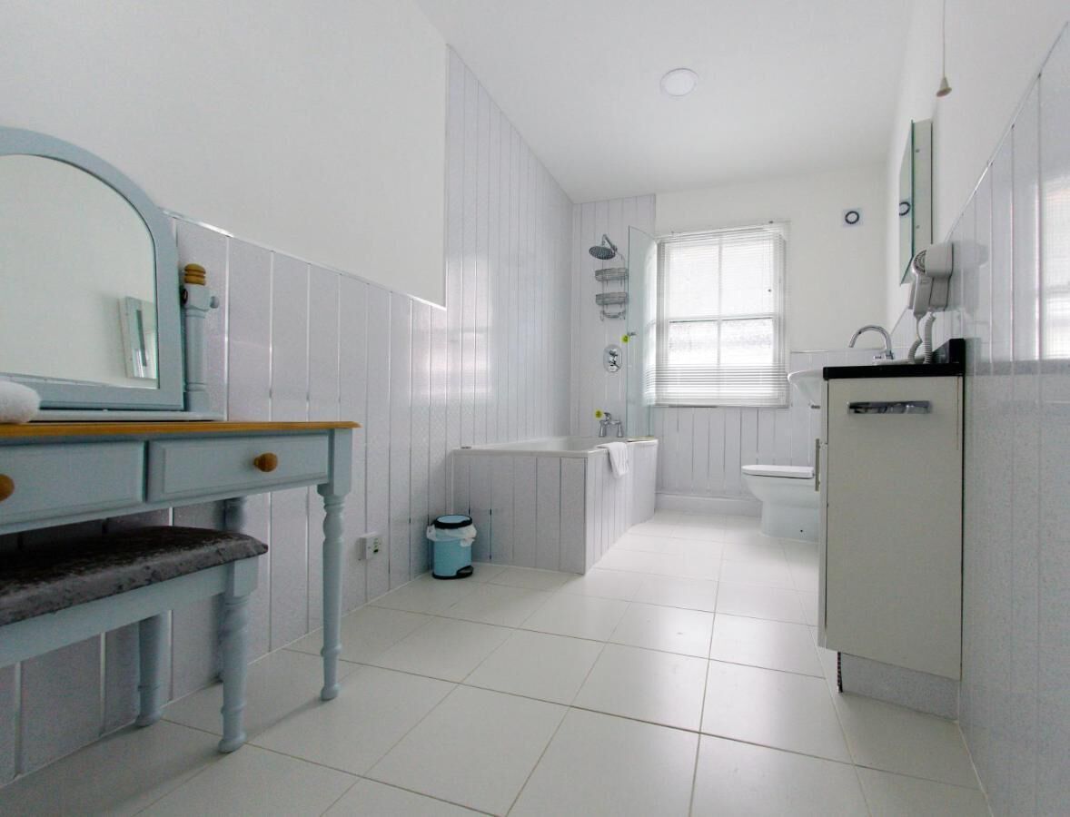 Un baño con lavamanos, espejo y retrete.