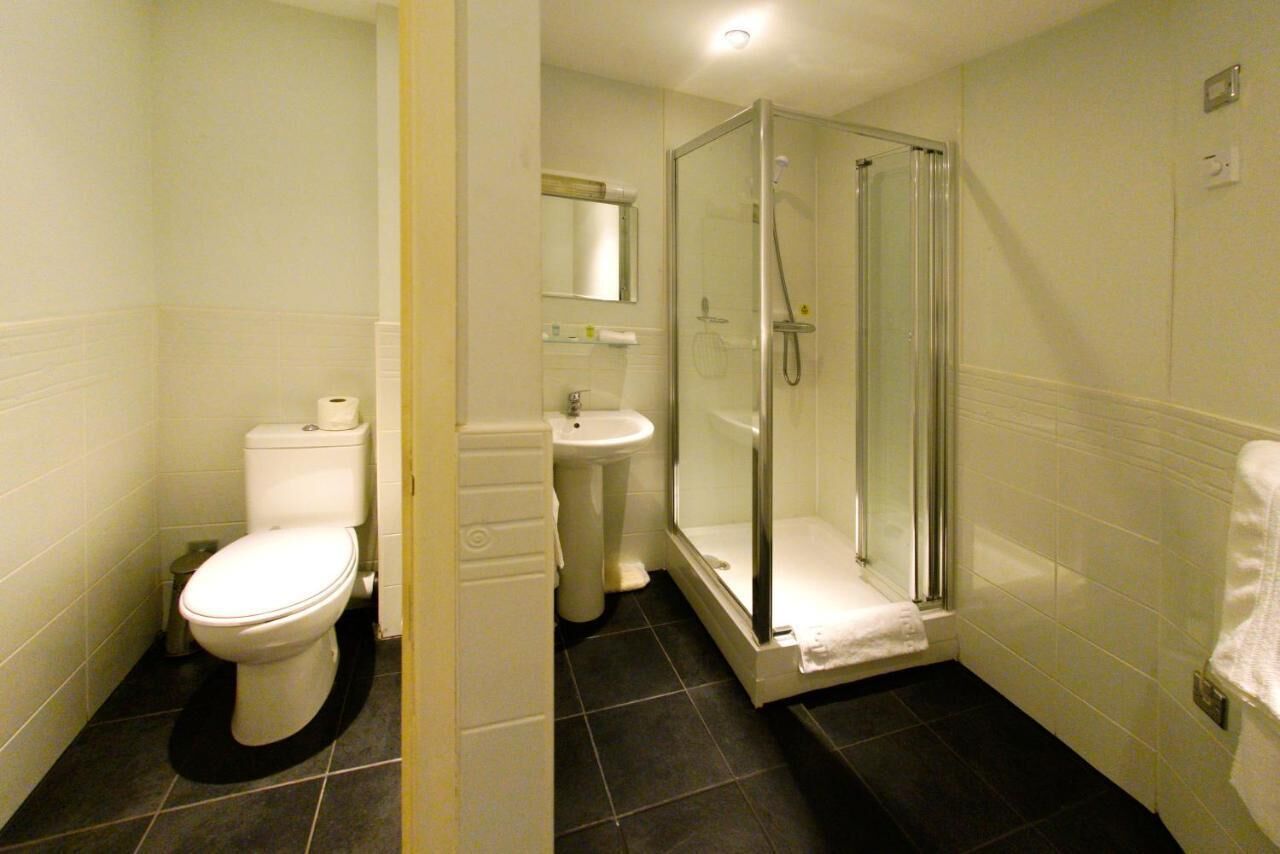 Een badkamer met toilet, wastafel en douchecabine.