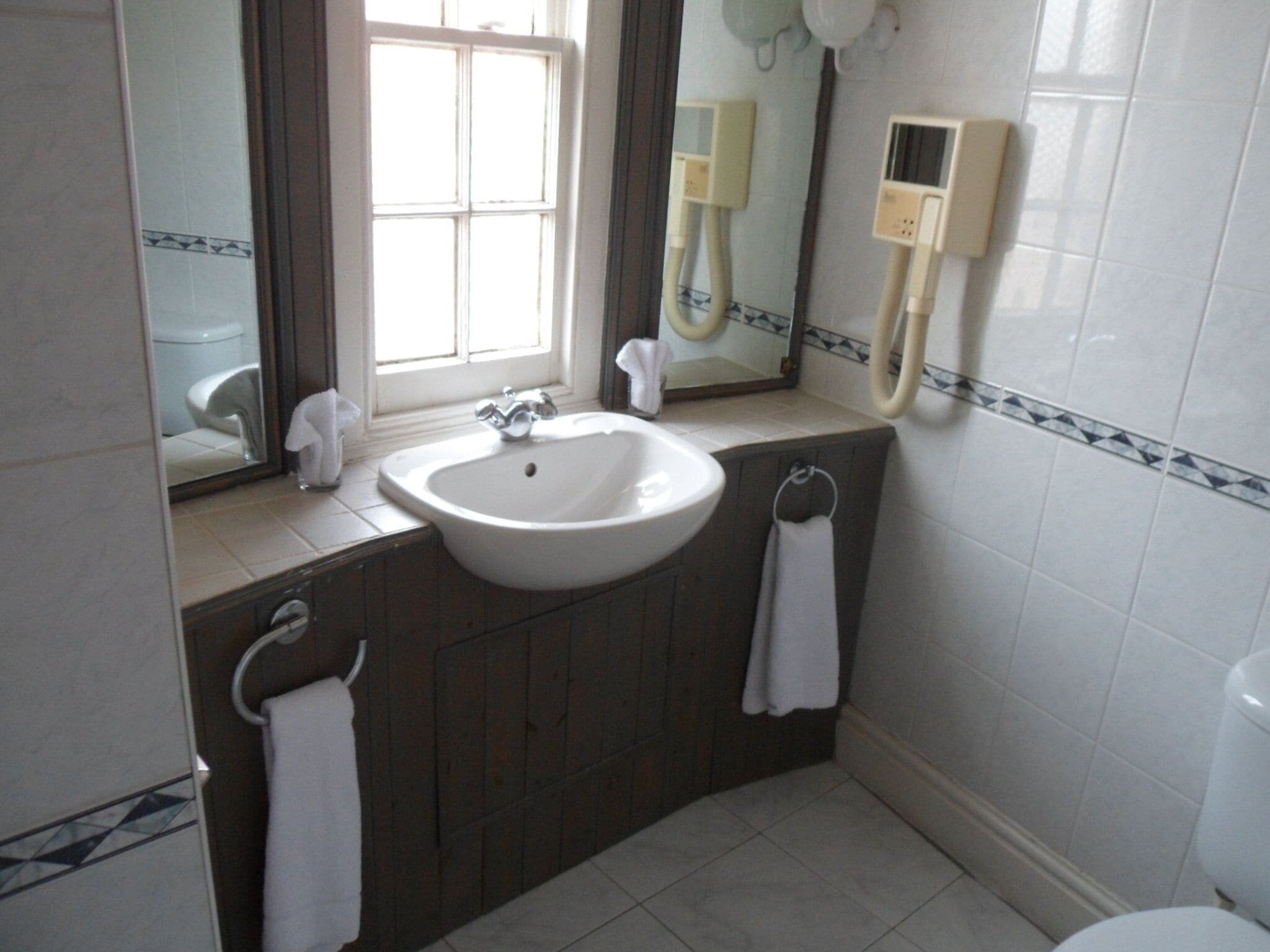 A bathroom with a white sink, a mirror, a towel rack, and a toilet.
