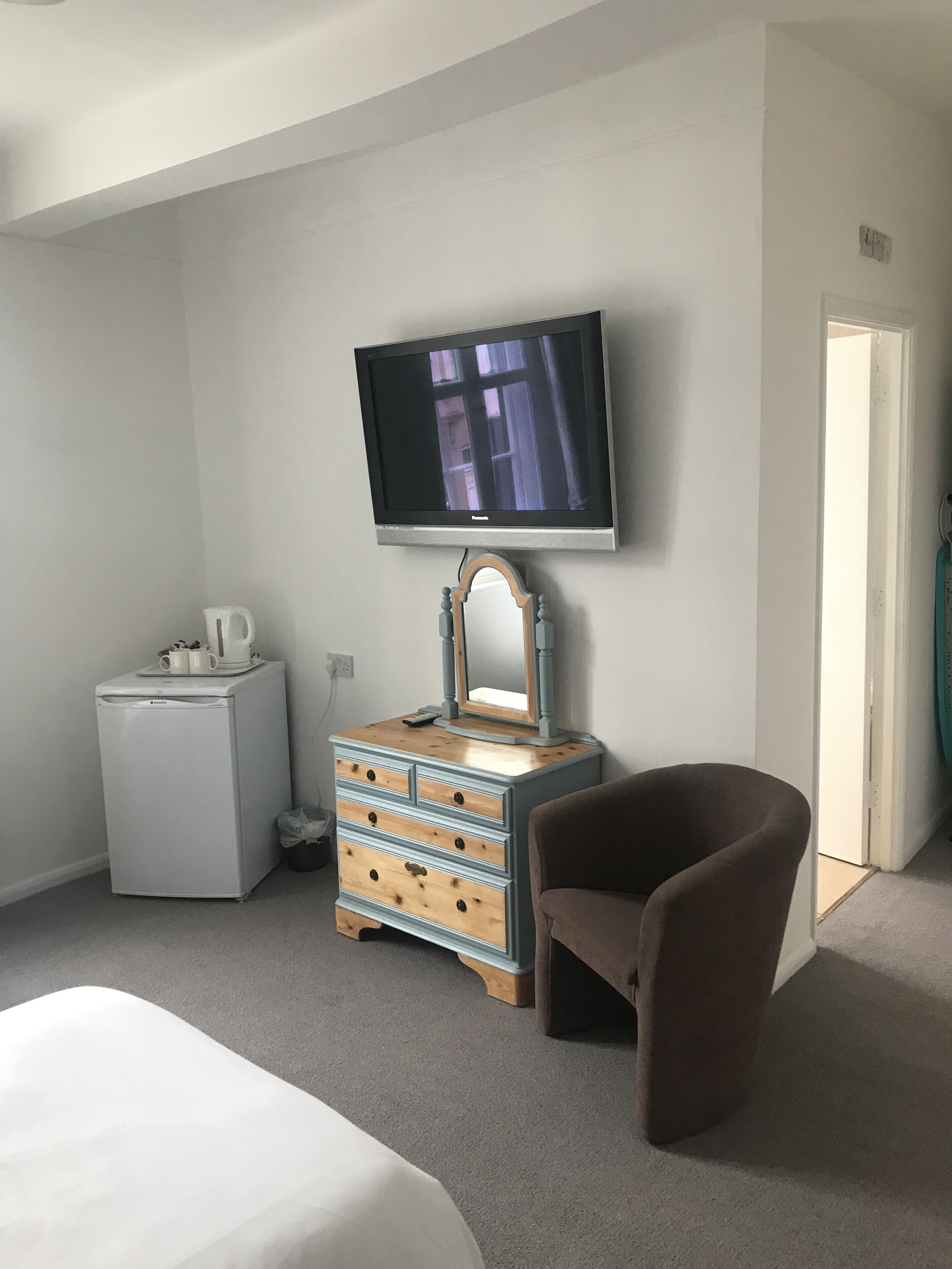 Habitación de hotel con cama, cómoda, televisor y una silla.