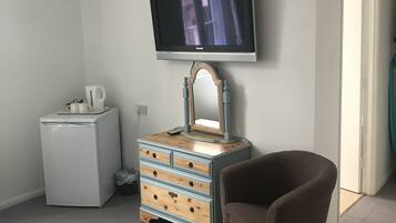 A hotel room with a bed, a dresser, a television, and a chair.