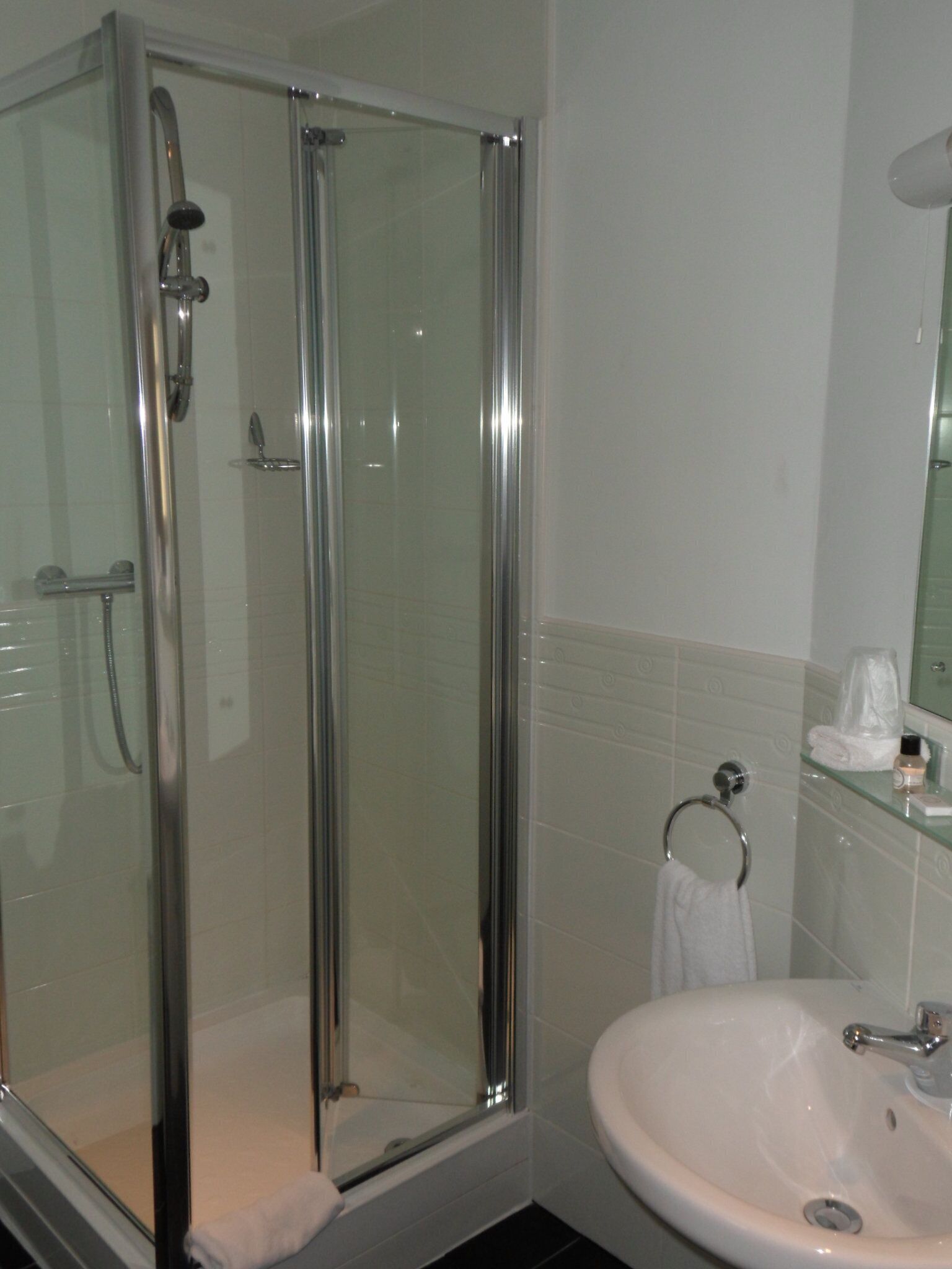 A bathroom with a glass-enclosed shower, a white sink, and a mirror above the sink.