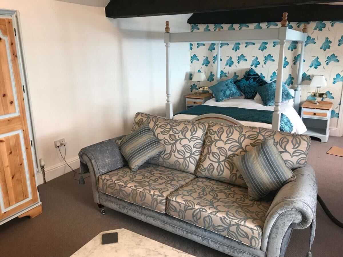 Un dormitorio con cama con dosel, un sofá y una mesita de noche.