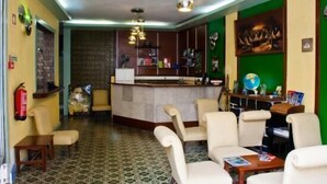 A lobby with a reception desk, seating area, and a green accent wall. - Residencial Monaco 38051-AL (Funchal)